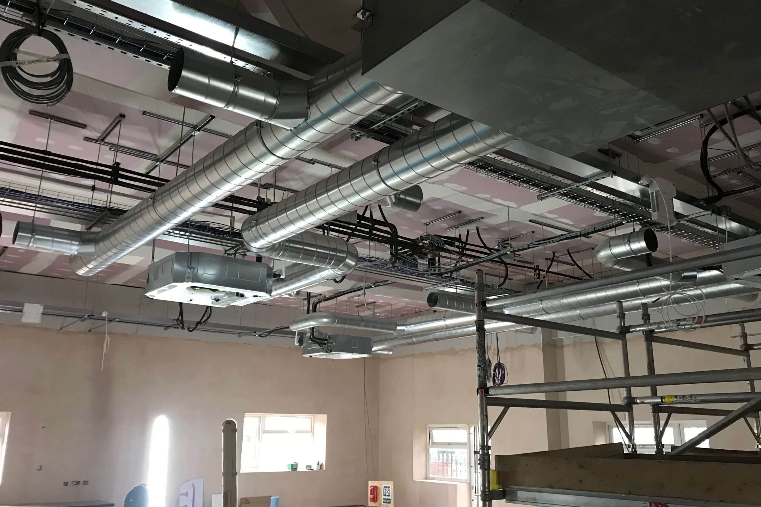 Norwood junction large commercial air conditioning solution by SubCool FM hanging unit amongst pipes in ceiling building view