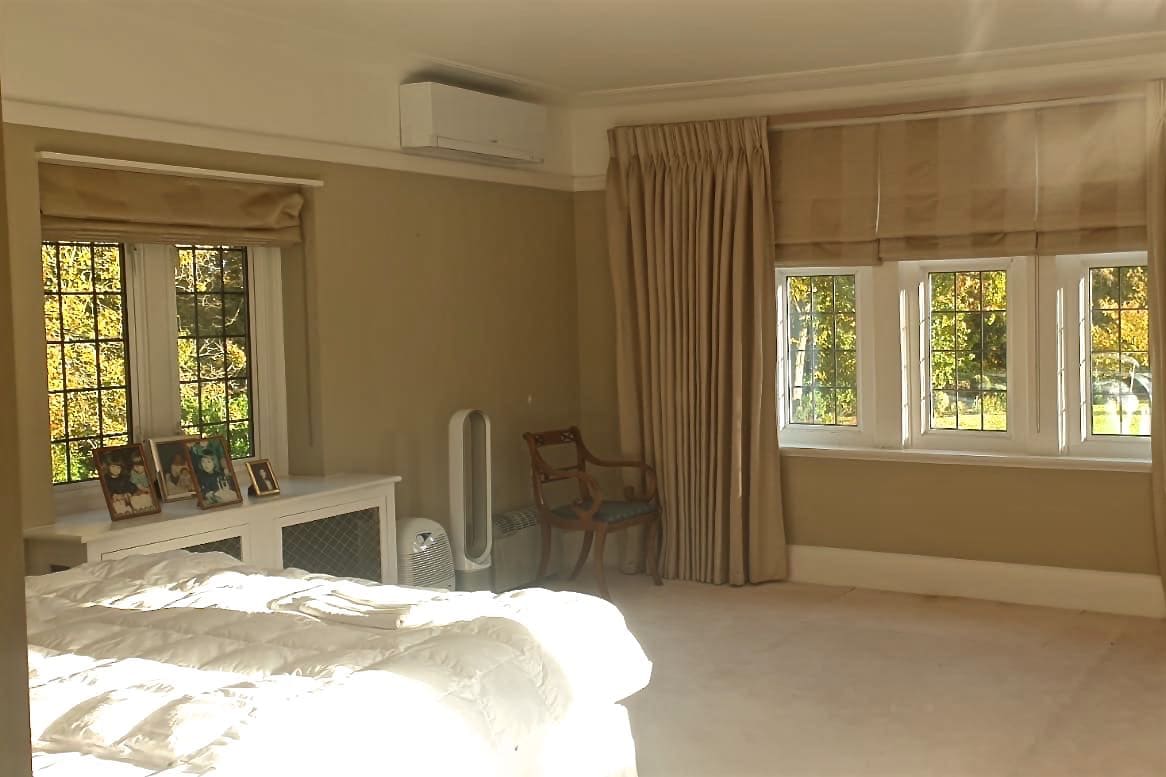 White wall mounted domestic air conditioning unit in beige large bedroom fitted by SubCool FM