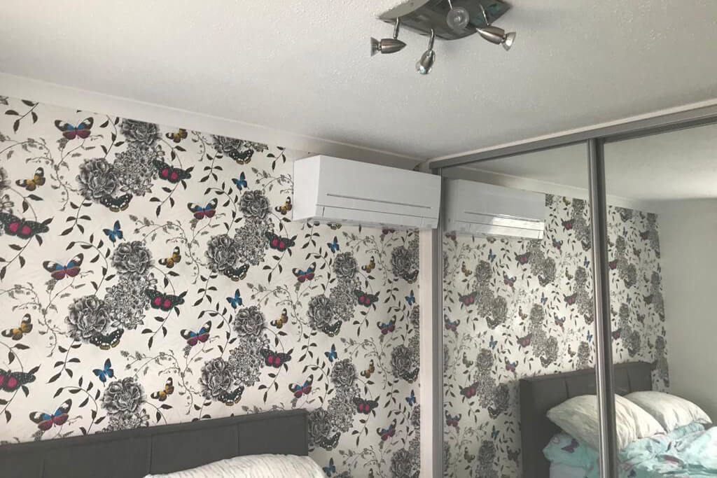 Air conditioning kent indoor unit in wallpapered bedroom with mirror wardrobe