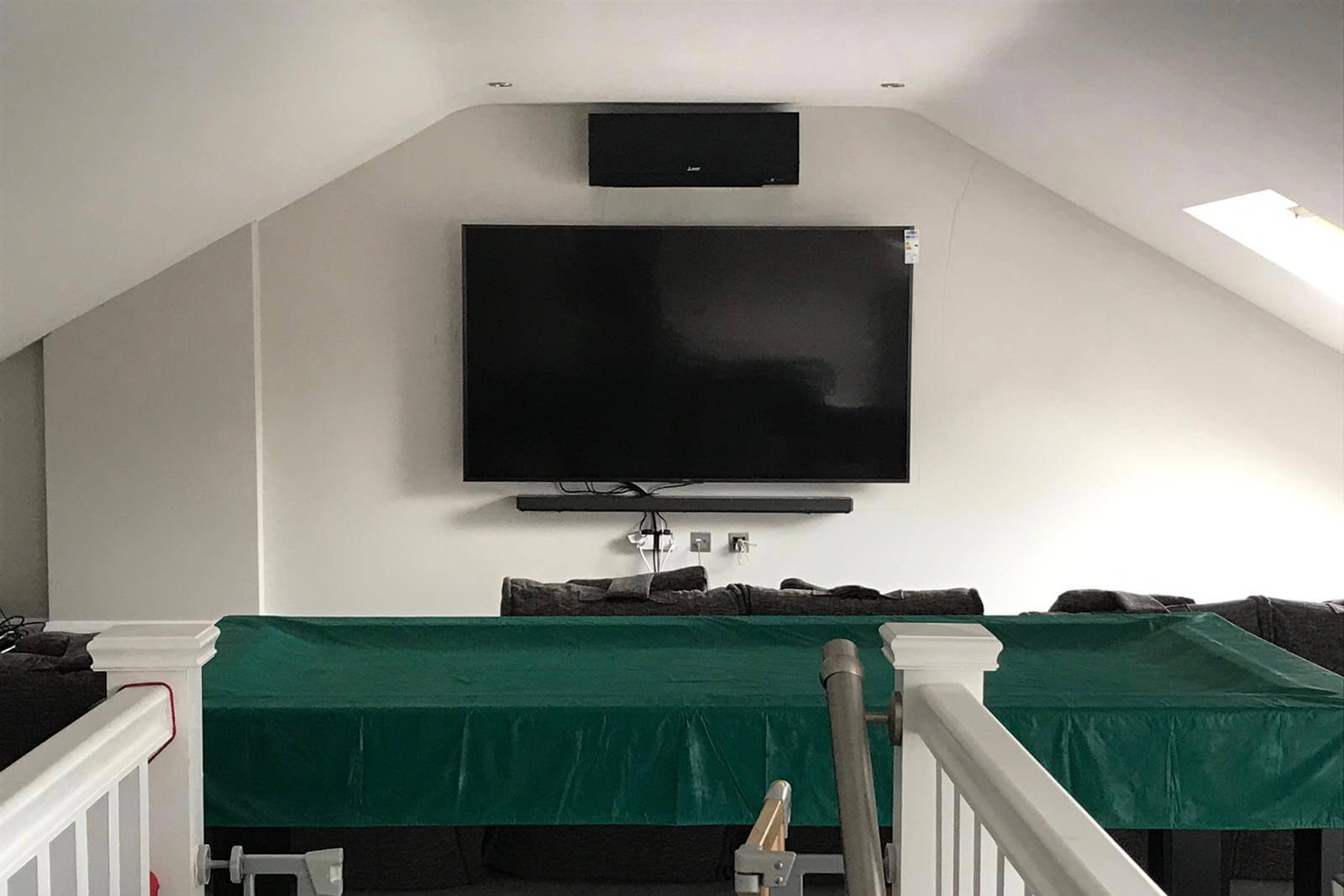 Black mitsubishi electric wall mounted unit above TV in loft conversion