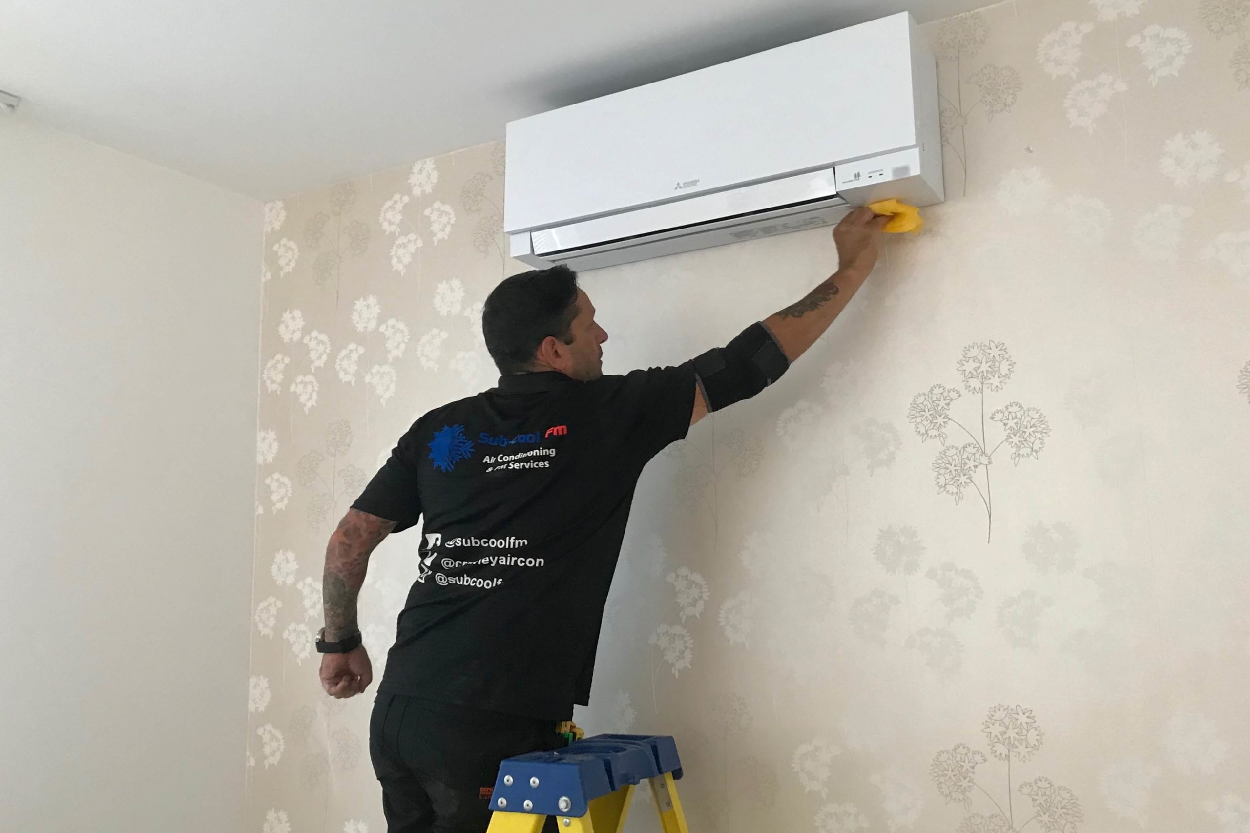 SubCool FM engineer working on white Mitsubishi Electric wall mounted air conditioning unit