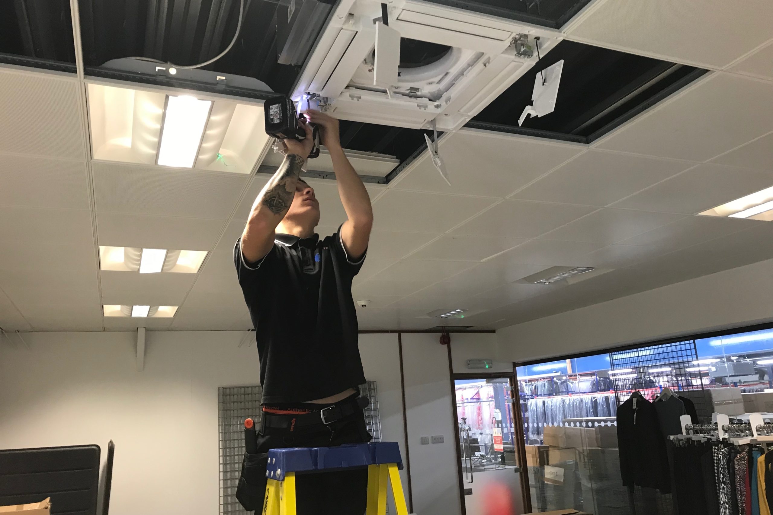 SubCool Fm air conditioning engineer drilling ceiling at clothing retailers